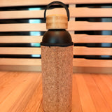 Bamboo water bottle with cork sleeve on a wooden surface