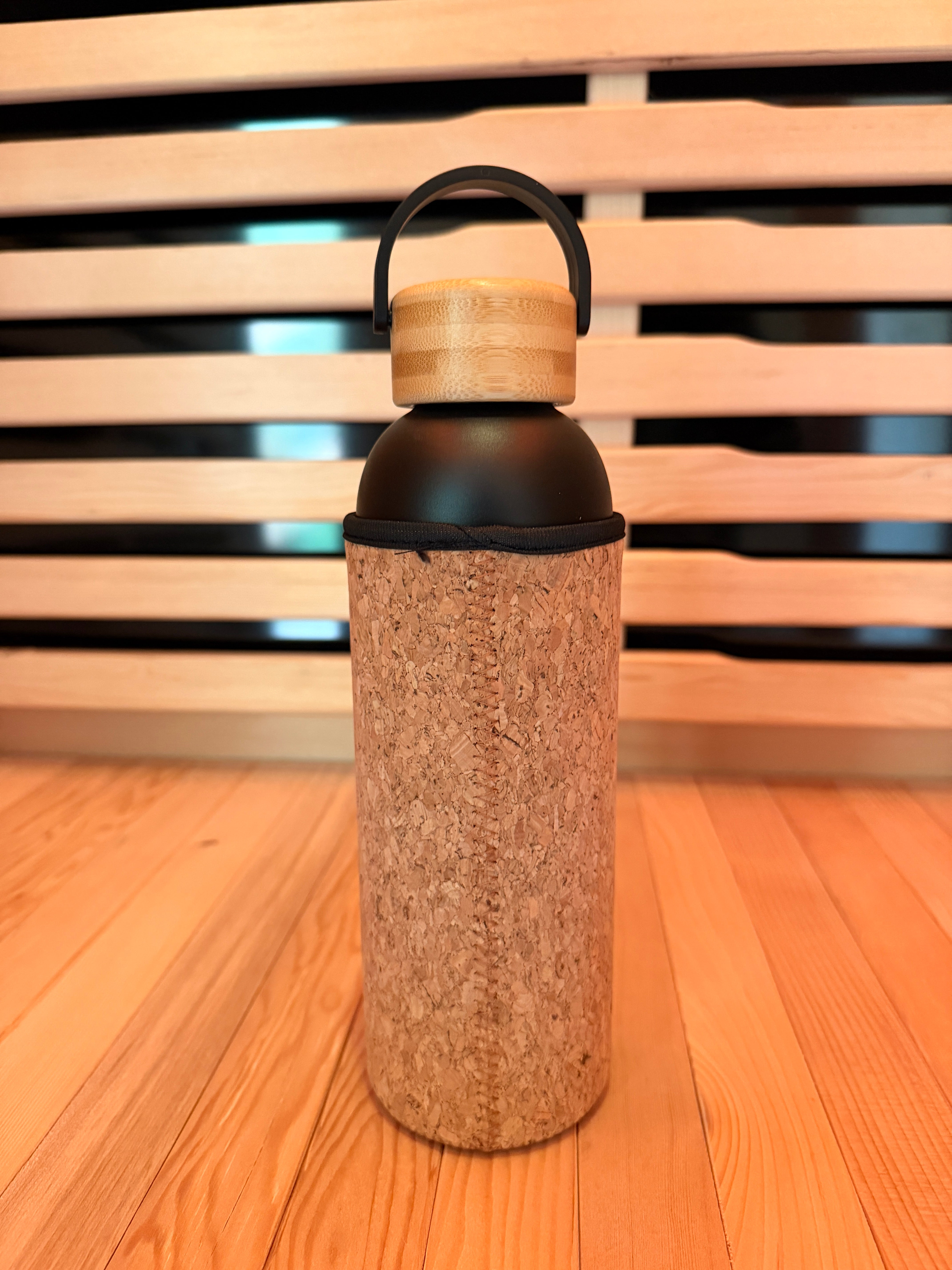 Bamboo water bottle with cork sleeve on a wooden surface