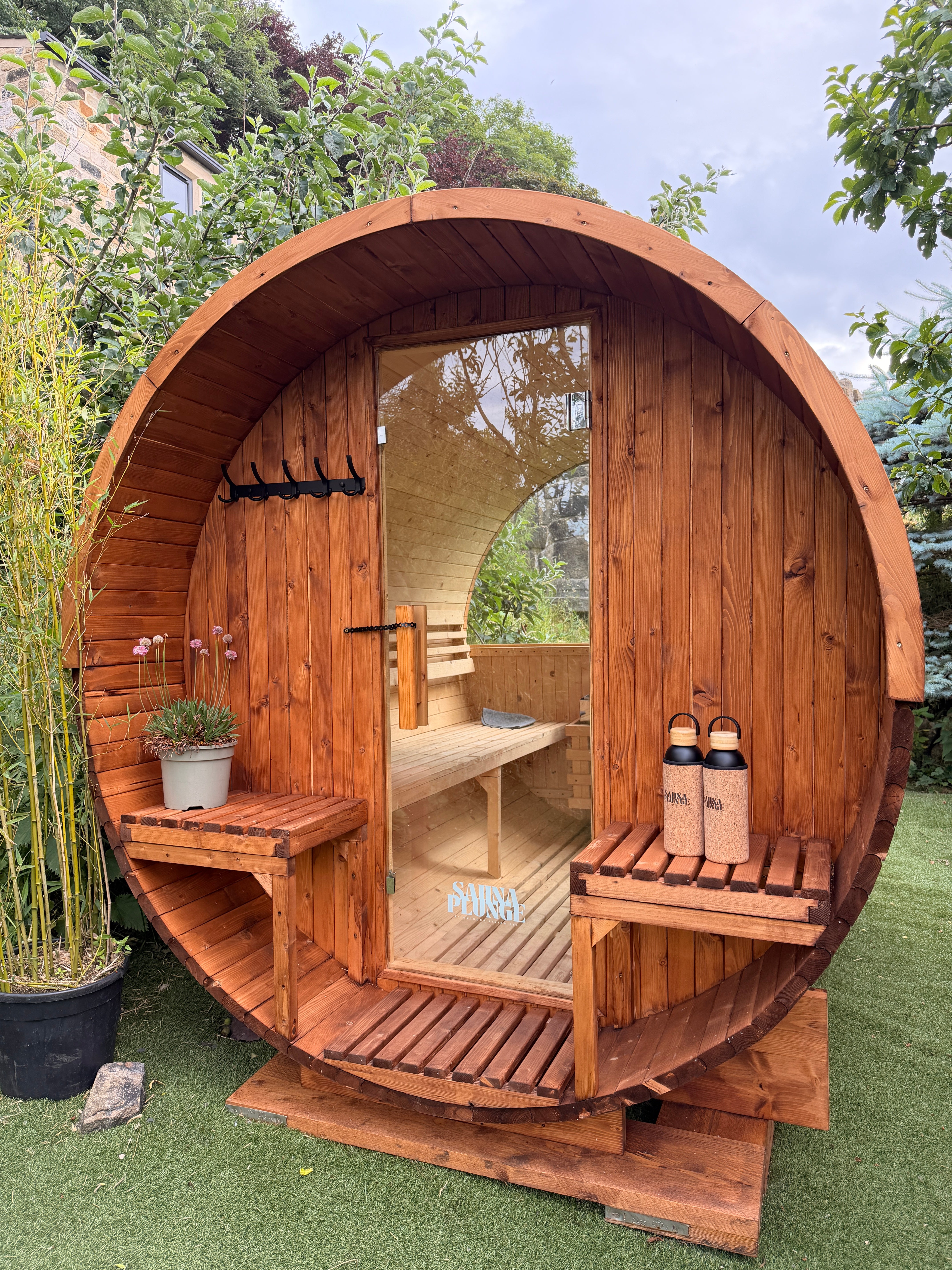 Wooden barrel-shaped structure with shelves and a door in an outdoor setting