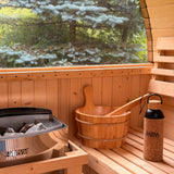 Wooden sauna interior with a bucket and a view of trees outside