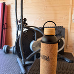 Cork-topped bottle on a chair with wooden floor and chair backrest in the background