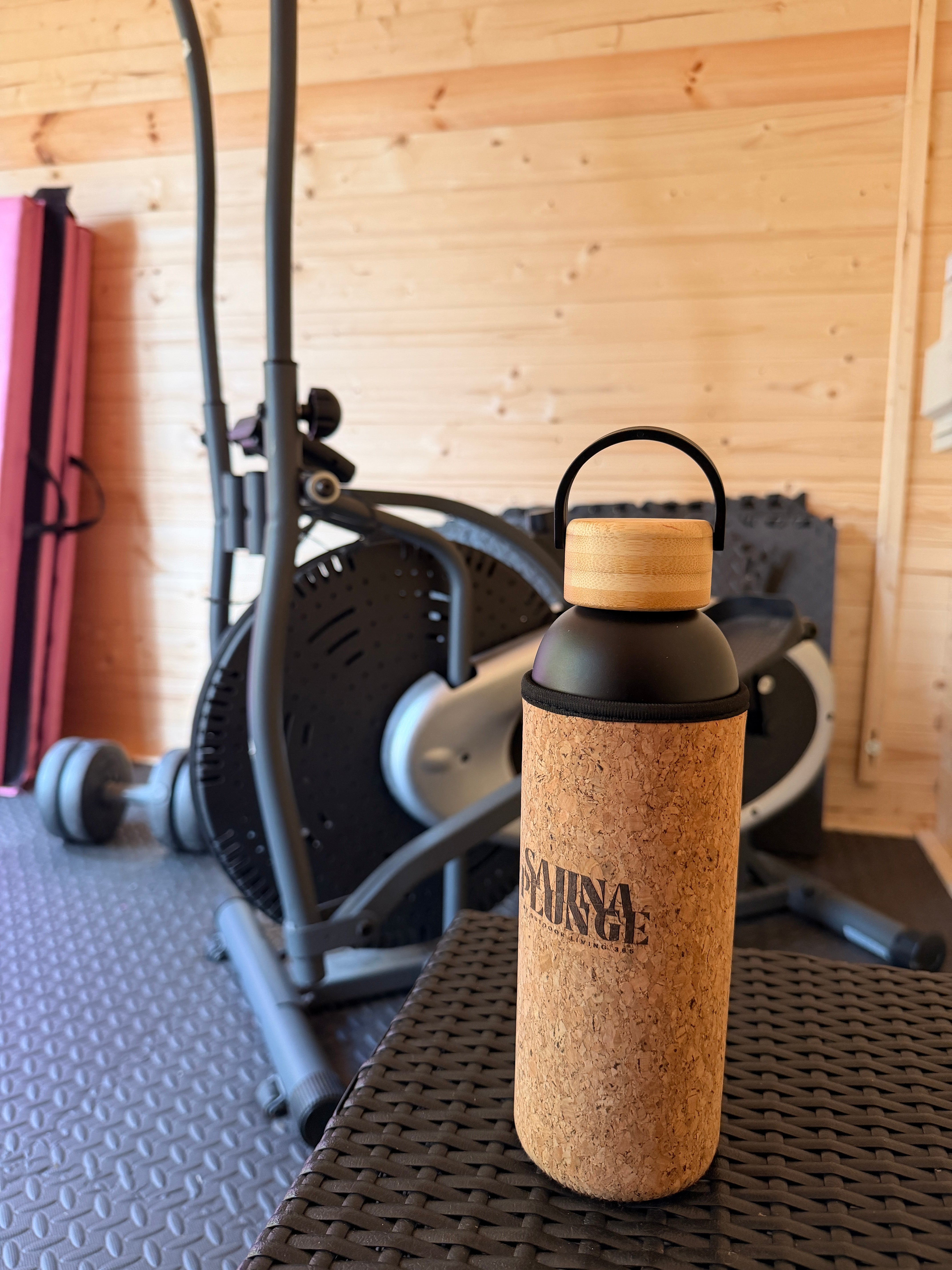 Cork-topped bottle on a chair with wooden floor and chair backrest in the background