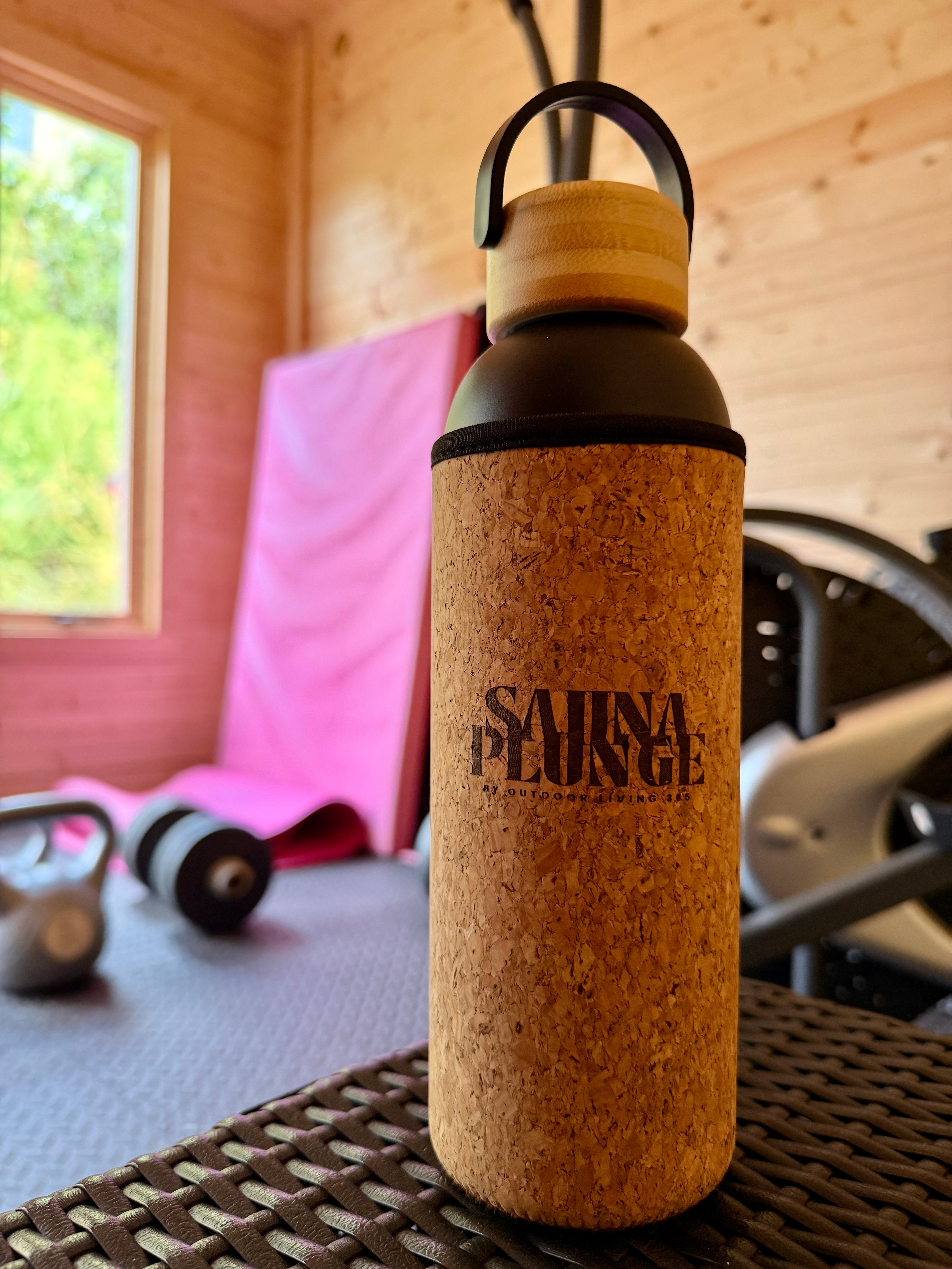 Cork-featured water bottle with 'SaunaPlunge' branding on a wooden surface.