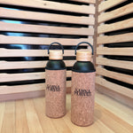 Two corked water bottles with black lids on a wooden surface.