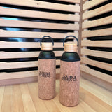 Two corked water bottles with black lids on a wooden surface.
