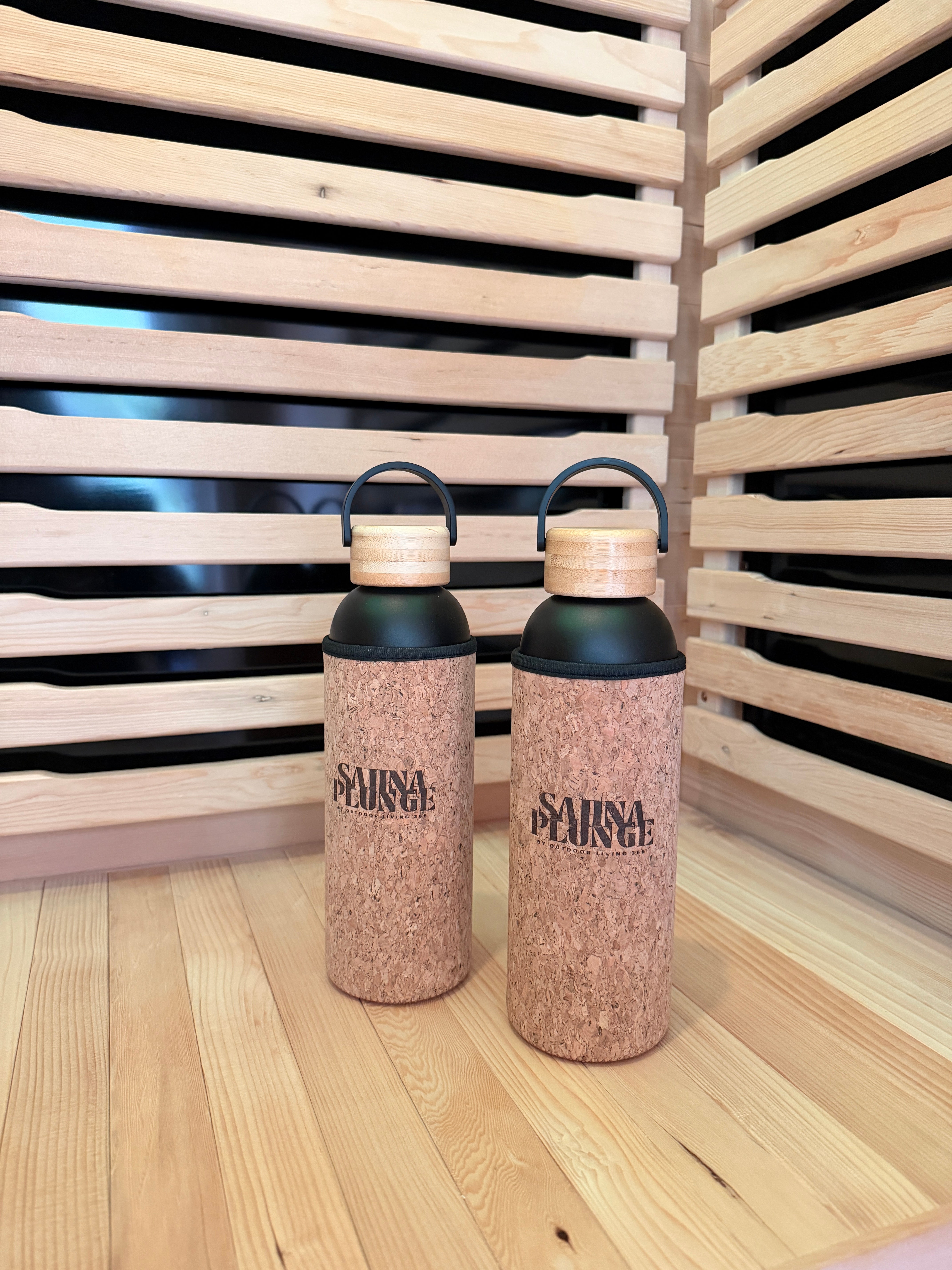Two corked water bottles with black lids on a wooden surface.